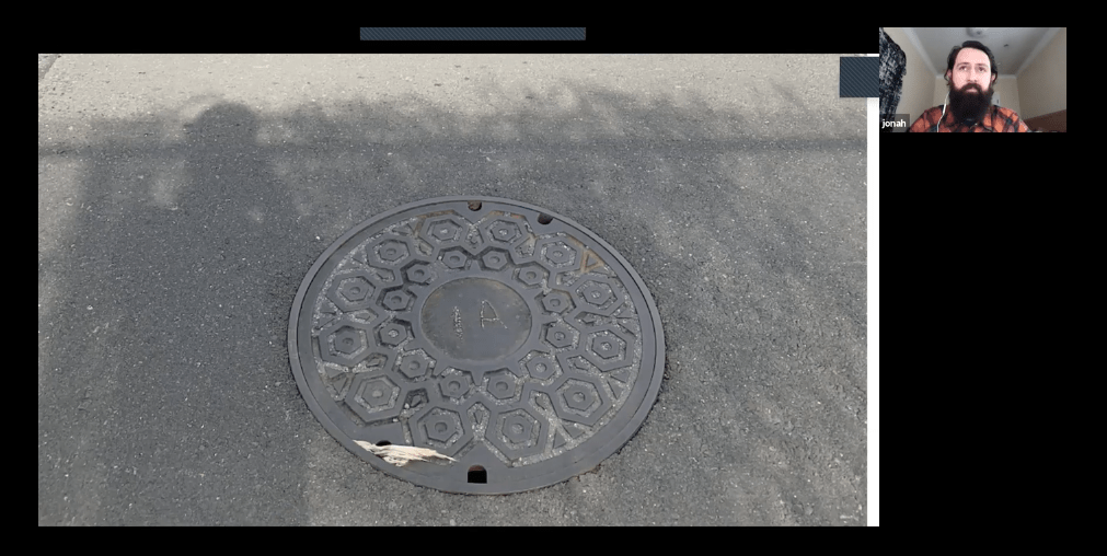 Screenshot from a video showing a manhole cover with a custom glyph for the Internet Archive inscribed on it.